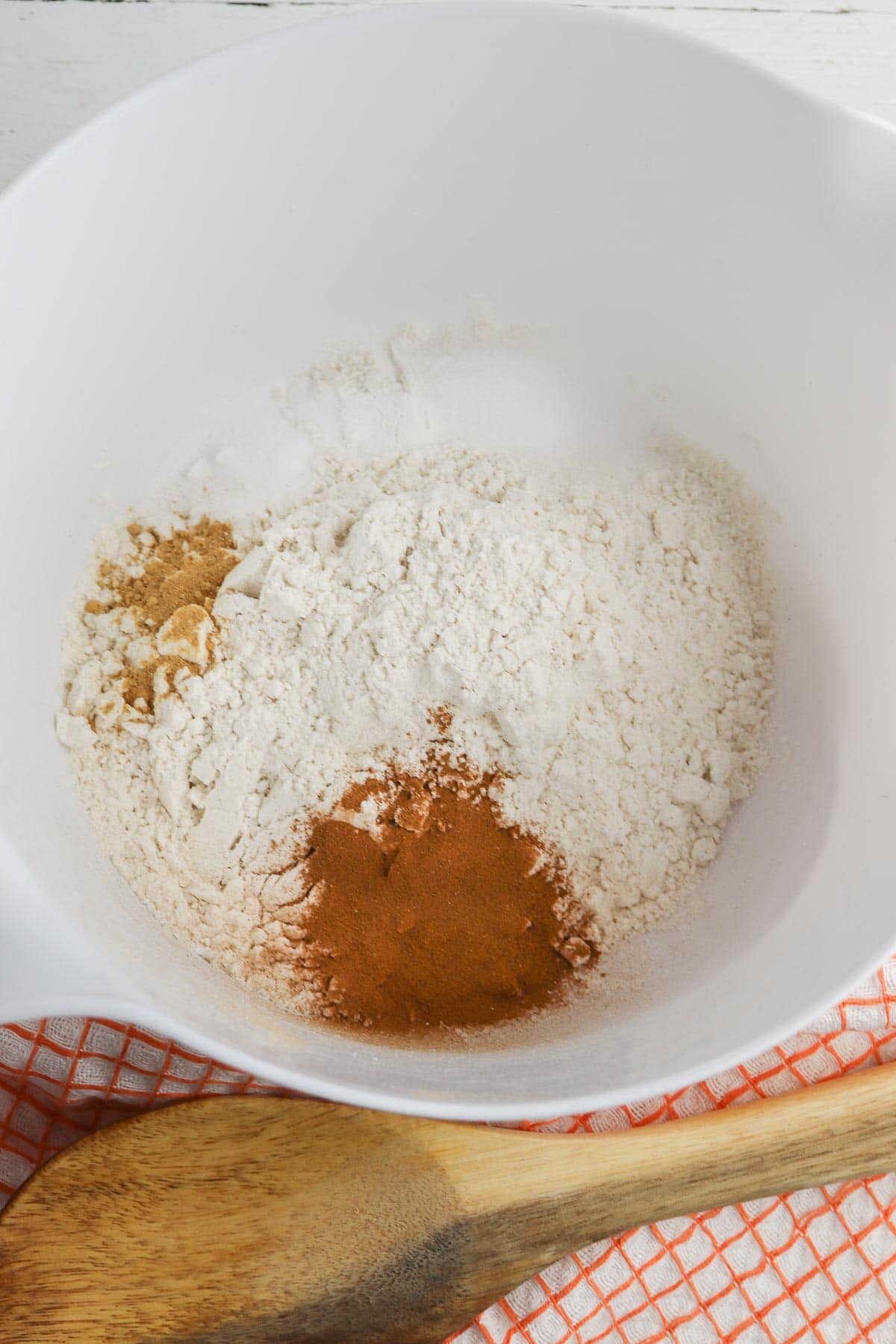 white mixing bowl with flour, cinnamon and nutmeg