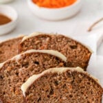 four slices of carrot cake bread topped with frosting on white parchment paper