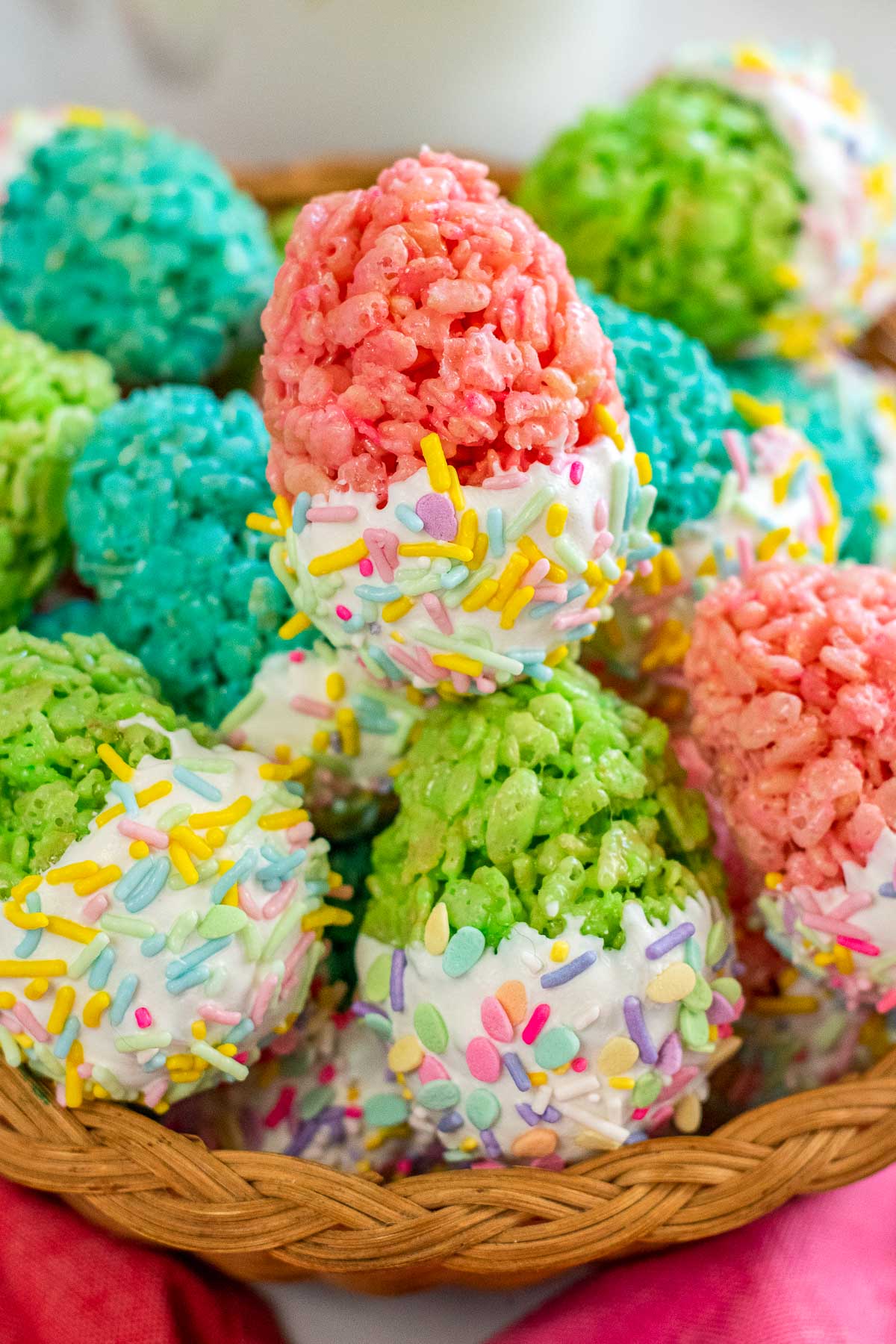basket full of pink, green and blue easter egg rice krispie treats with sprinkles and white chocolate