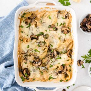 white rectangle casserole dish with cheesy stuffed shells in a white alfredo sauce with mushrooms