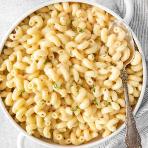 closeup of mac and cheese in a white serving bowl with an antique silver spoon