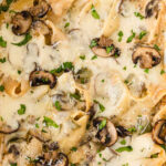 white casserole dish with jumbo pasta shells stuffed with philly cheesesteak mixture