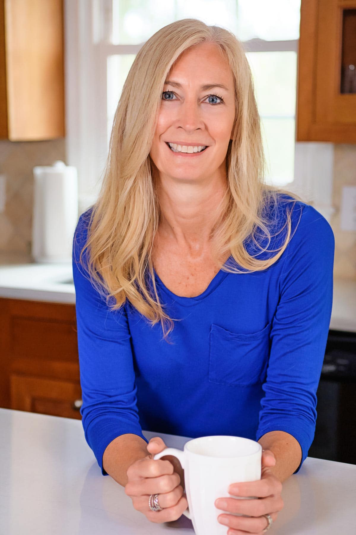 Sherri Hagymas leaning on a counter with a white coffee mug