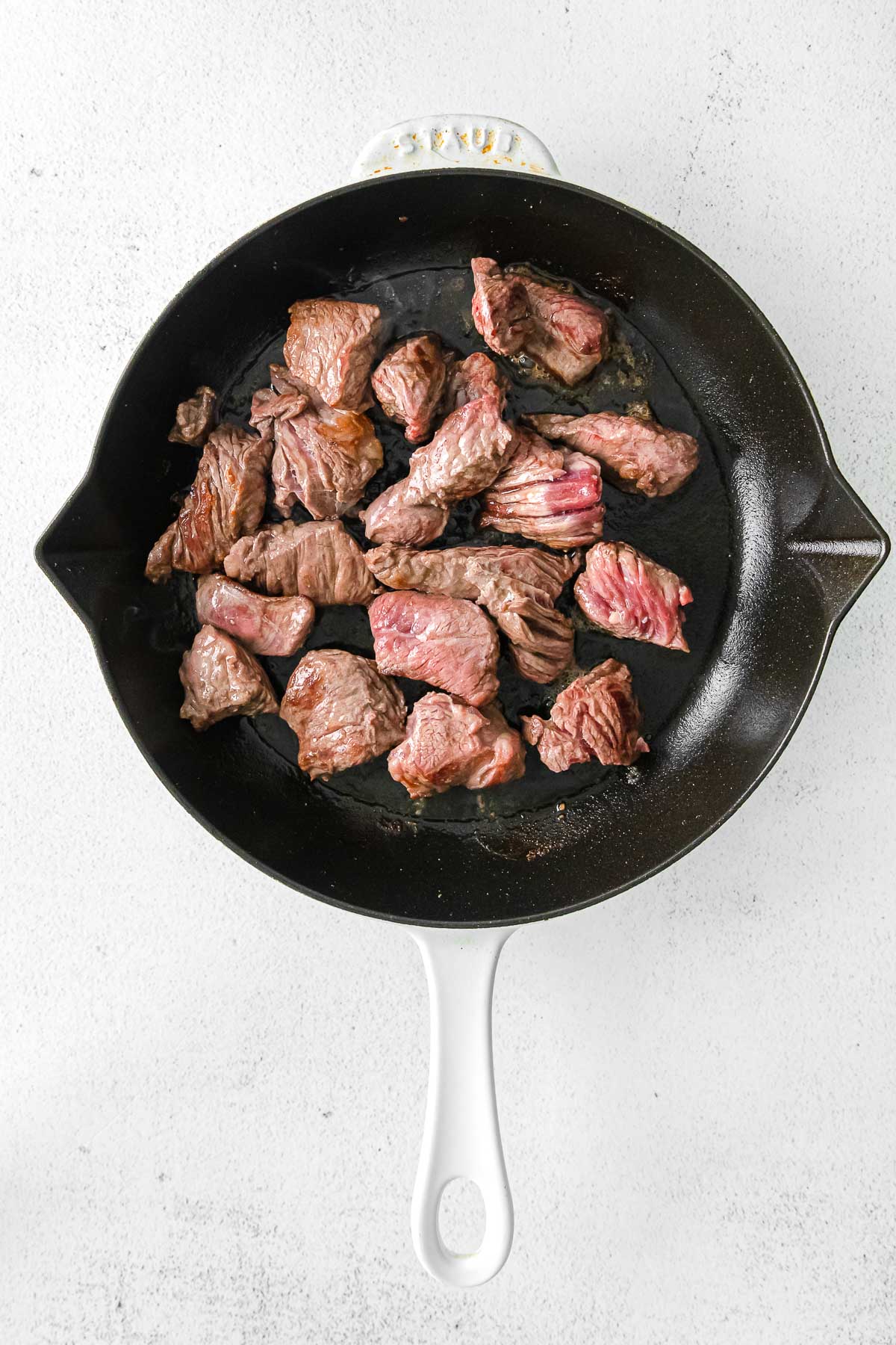 cast iron pan with chunks of steak