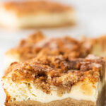 closeup of cheesecake bars with snickerdoodle cookie base and crumble topping with text overlay