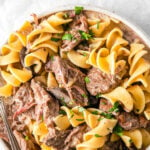 white bowl with beef stroganoff over egg noodles with text overlay that says "slow cooker beef stroganoff"