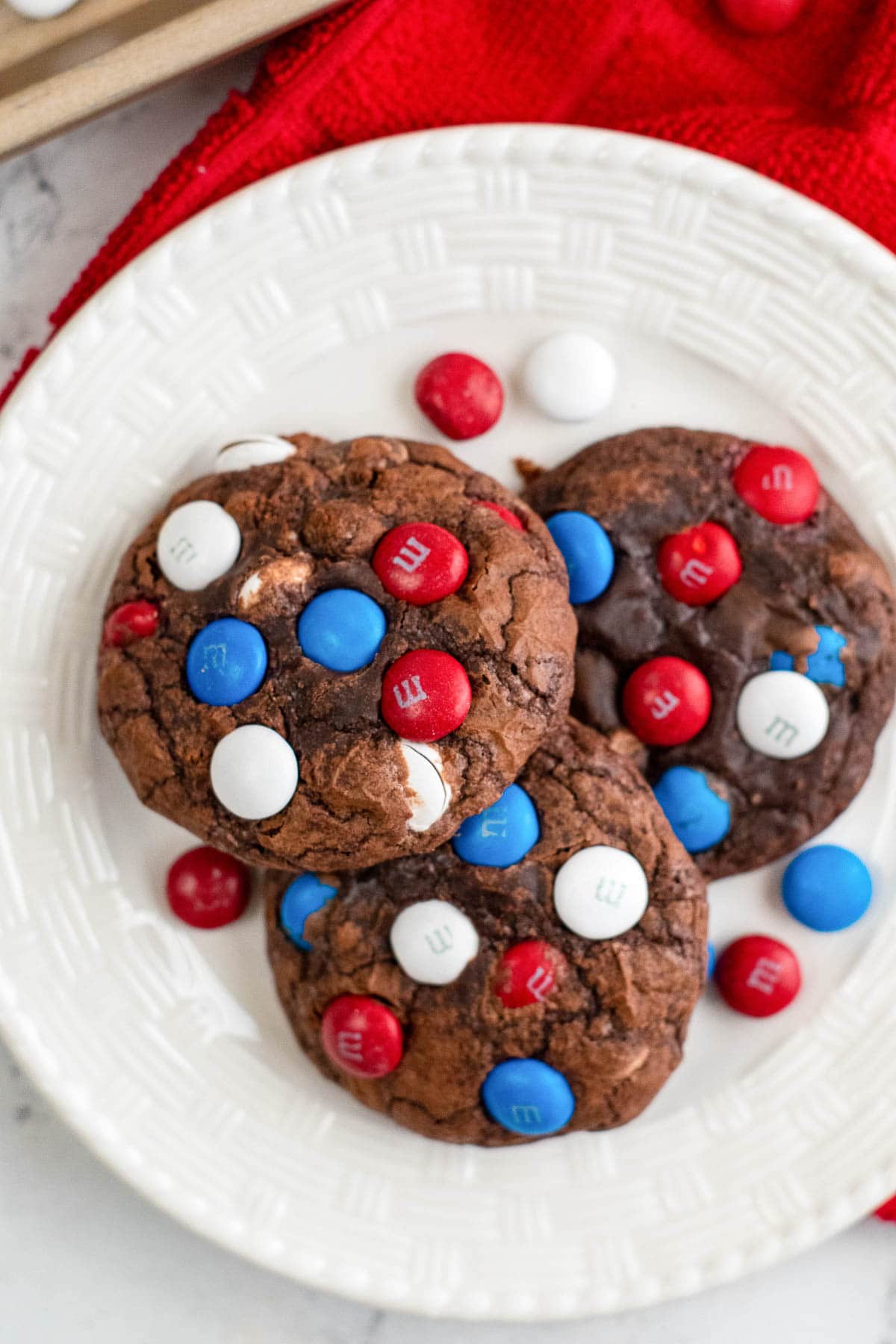 white plate with three chocolate brownie cookies with red white and blue M&M candies