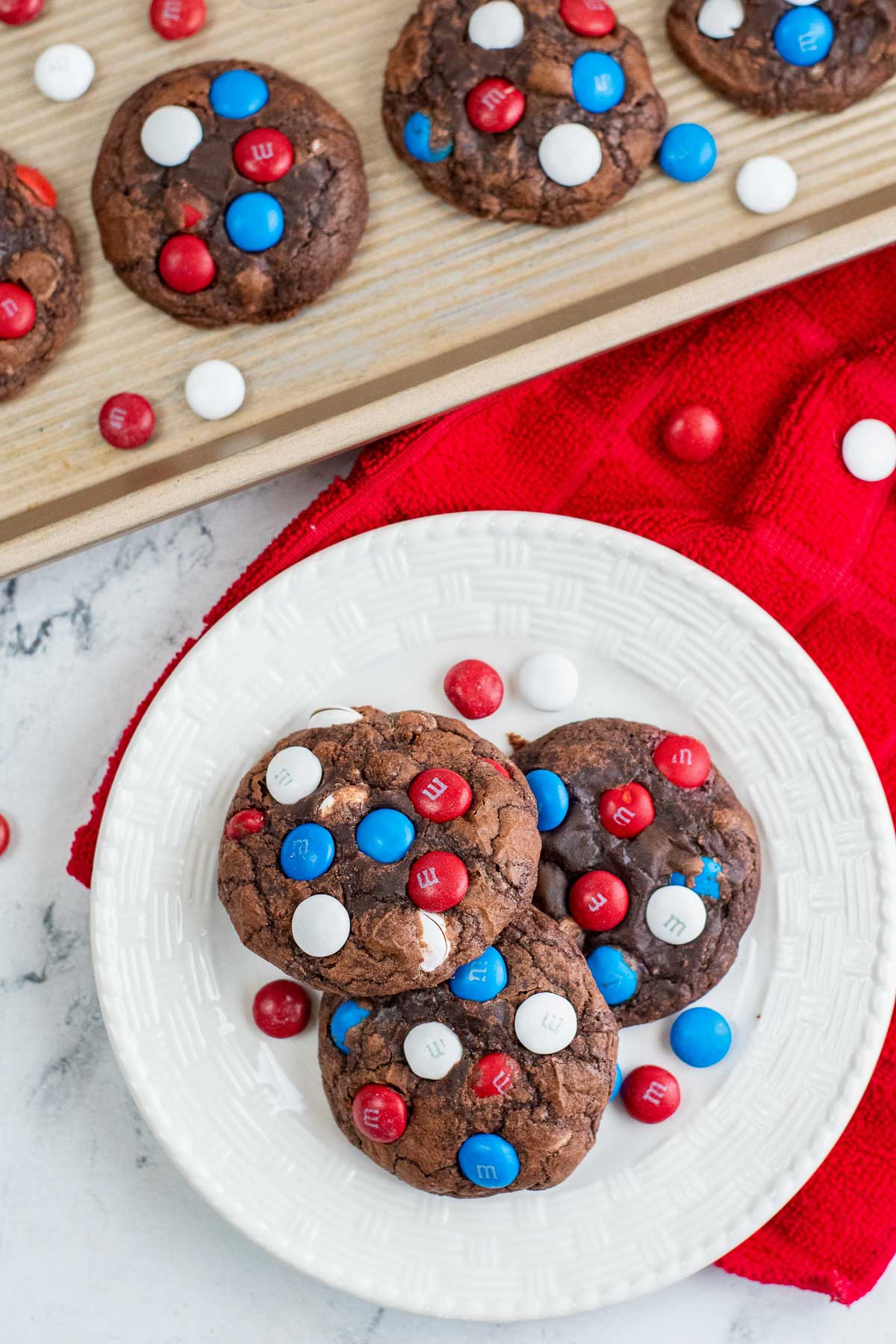 white plate with three chocolate cookies with red white and blue m&m's