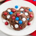 white plate with three chocolate brownie cookies with red white and blue m&m's