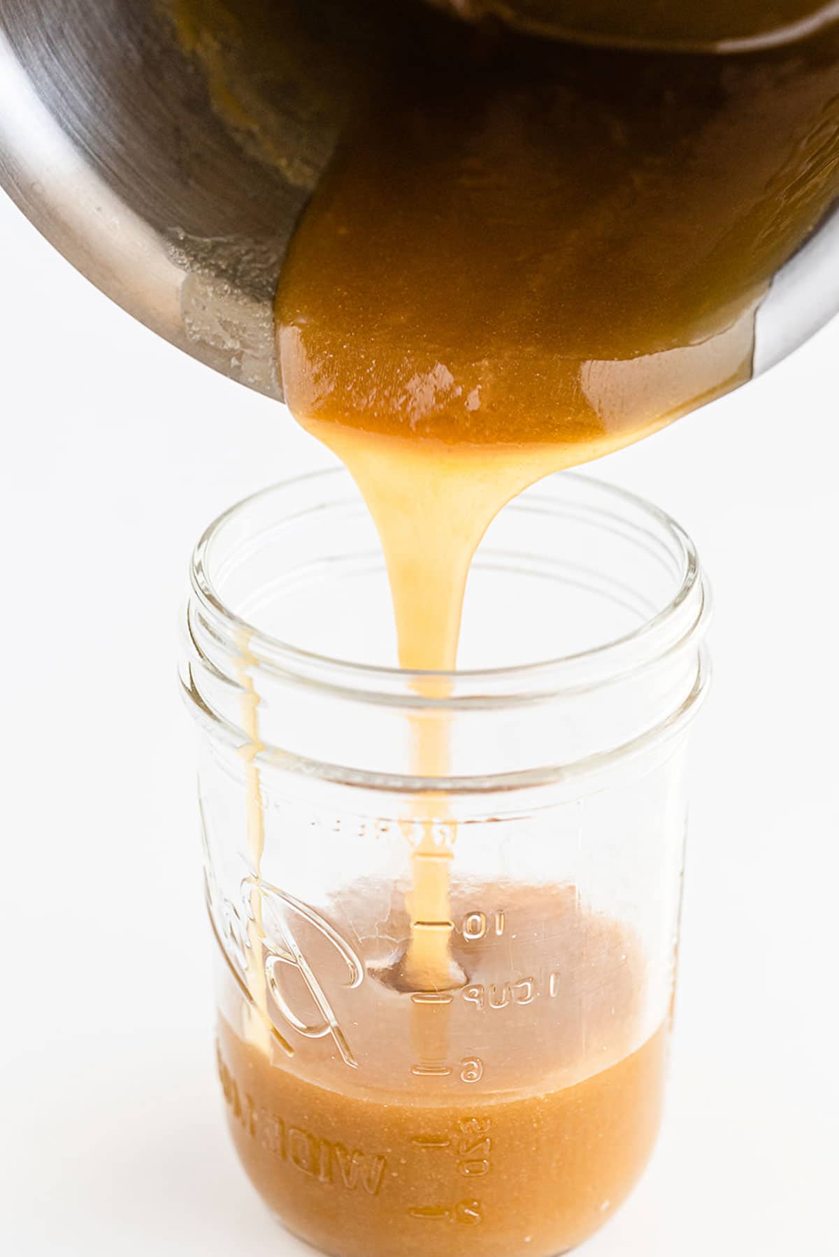 butterscotch sauce being poured into a small glass jar