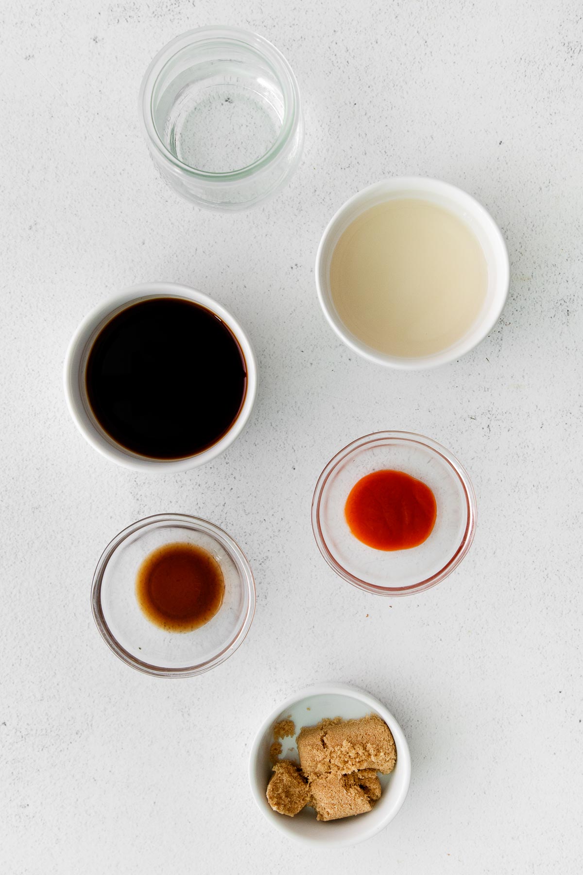 several small bowls with ingredients for thai stir fry sauce - brown sugar, soy sauce, fish sauce, water, and sriracha