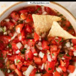 closeup of pico de gallo salsa with two tortilla chips dipped in