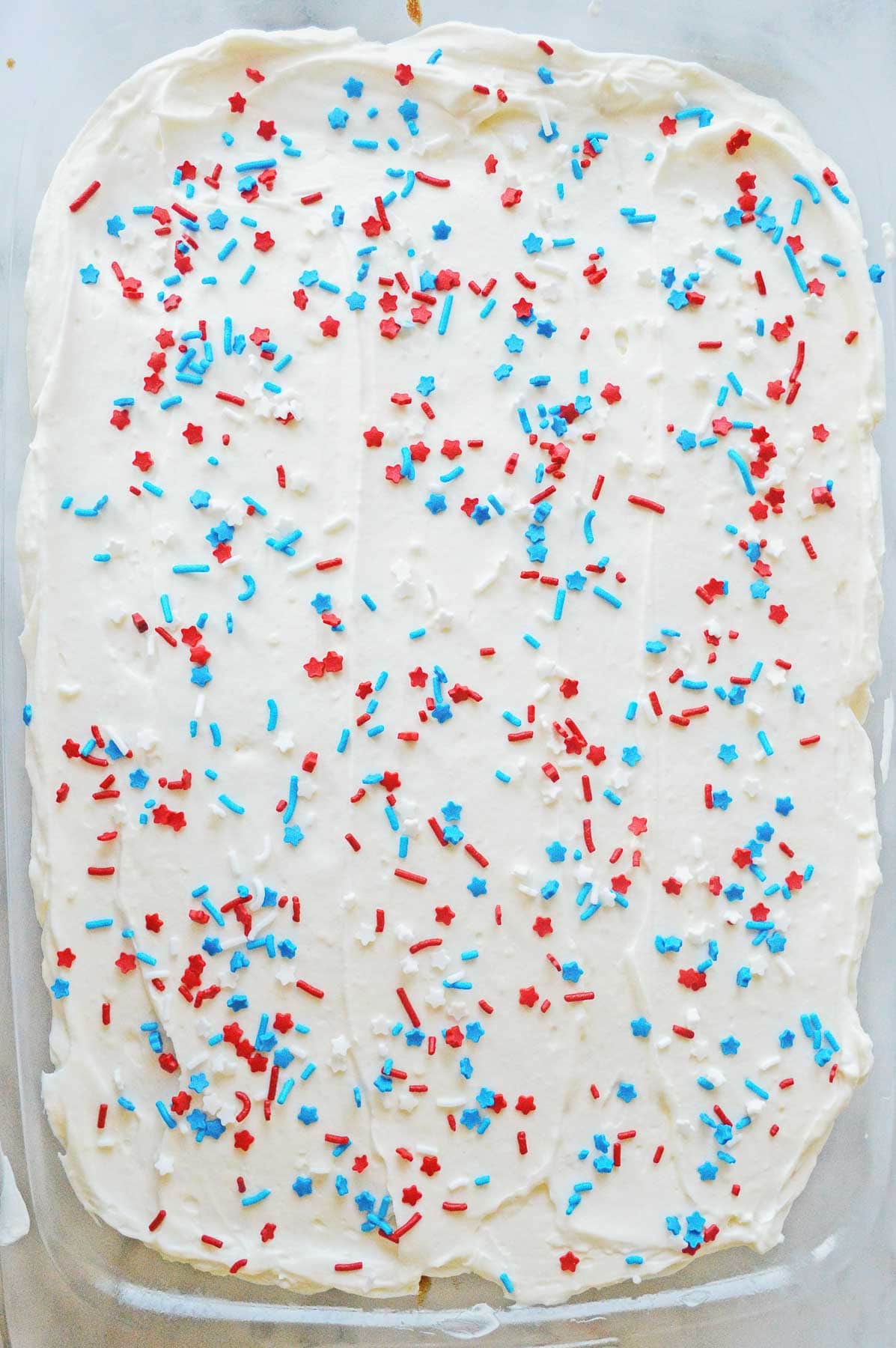 rectangle cake with white icing topped with 4th of july stars and stripes sprinkles
