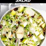 brussels sprouts salad with diced green apples with 2 antique spoons and text overlay reading shaved brussels sprouts salad