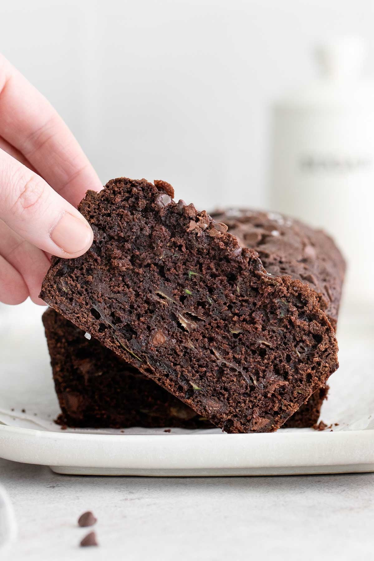 a slice of chocolate zucchini bread being picked up with a woman's fingers