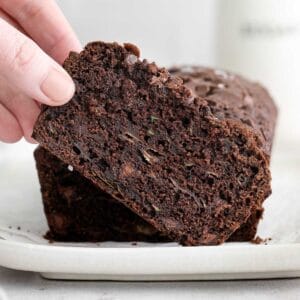slice of chocolate zucchini bread being picked up by woman's finger