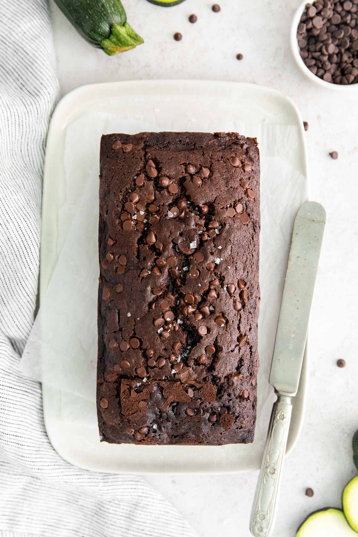 double chocolate zucchini bread with chocolate chips on a white plate with an antique knife.