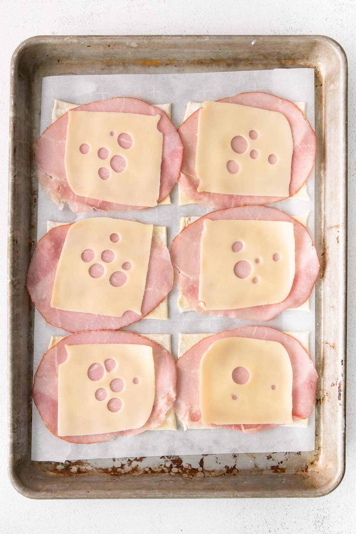 silver tray with six slices of ham topped with swiss cheese on top
