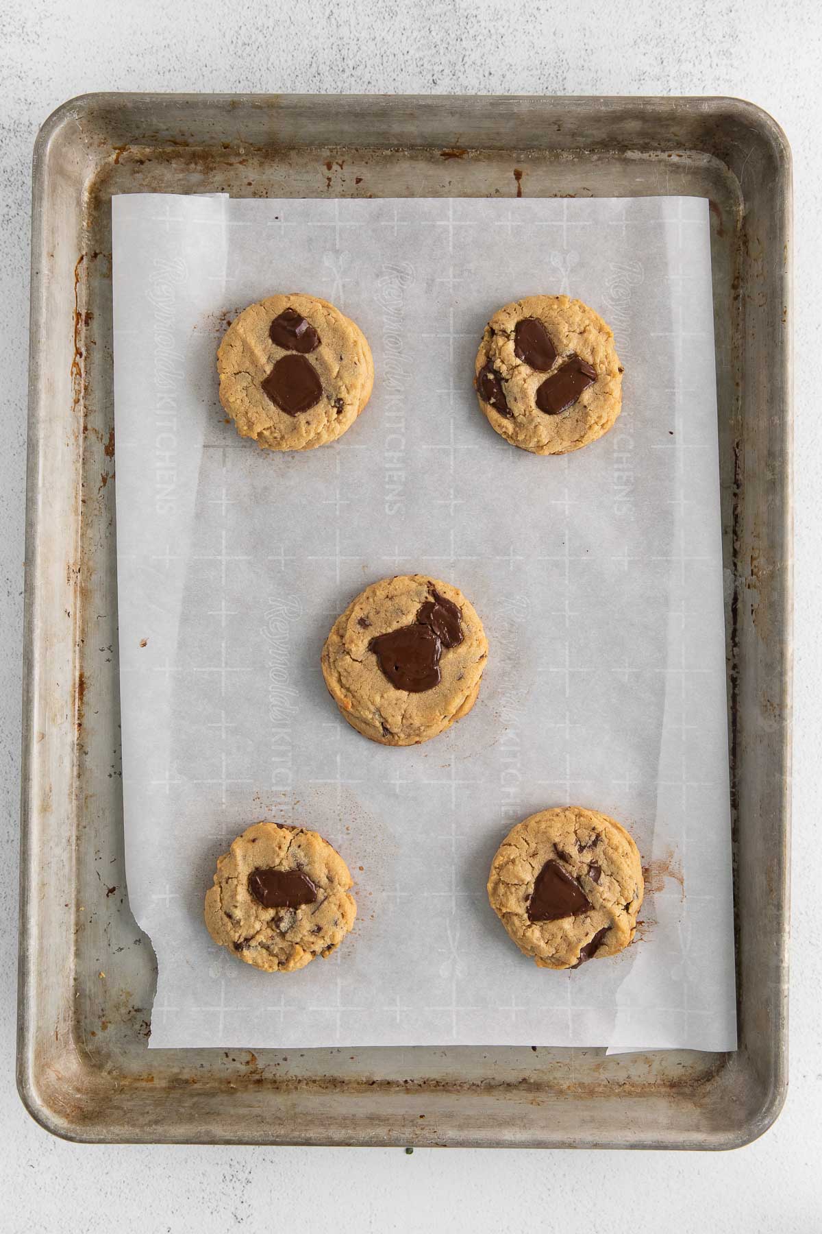 five baked peanut butter and chocolate chip cookies on a baking tray