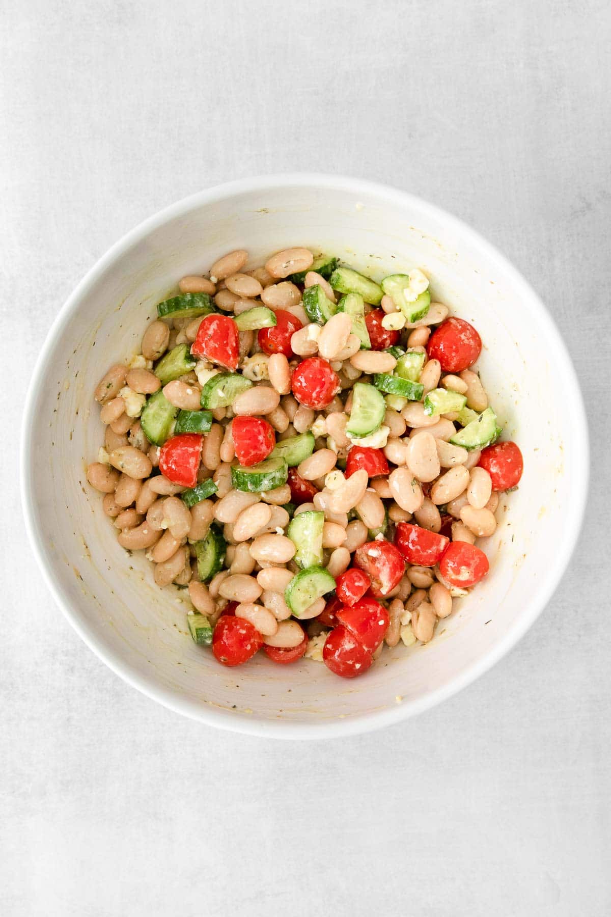 white bean salad with cucumbers and tomatoes in a white bowl