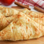 closeup of apple turnover drizzled with caramel on a wood cutting board