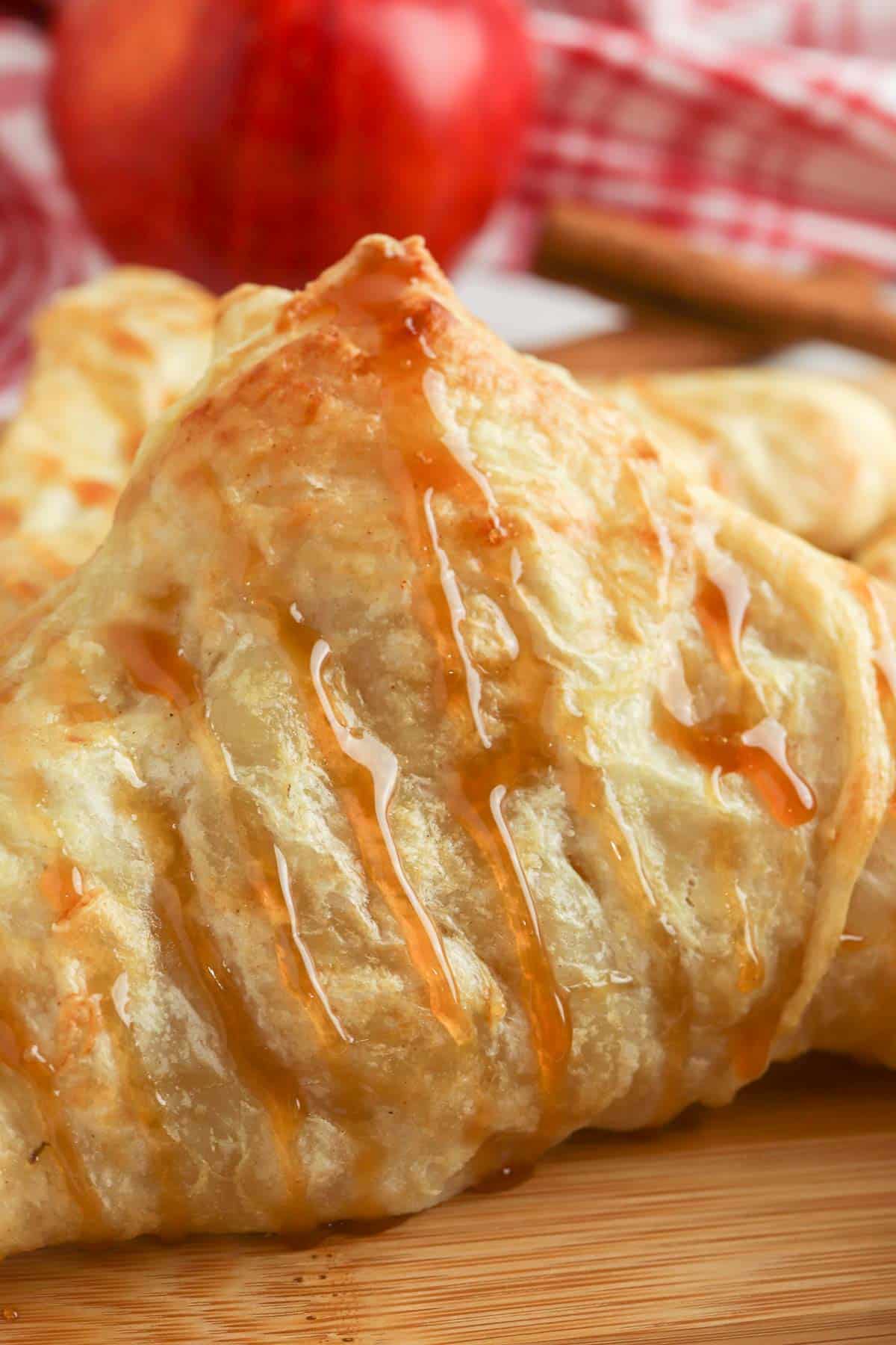 closeup of a golden brown apple puff pastry turnover with caramel drizzle.