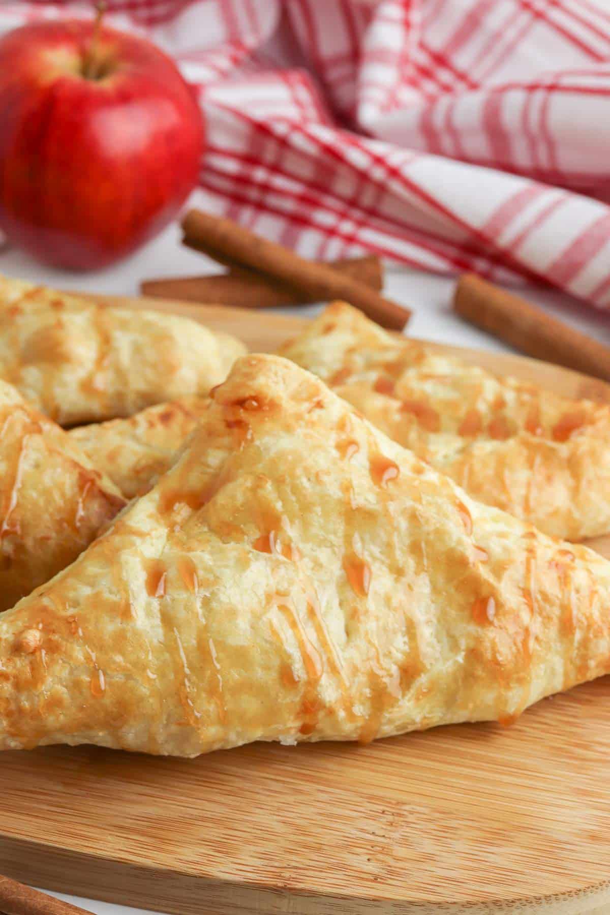 several apple turnovers on a wood cutting board.