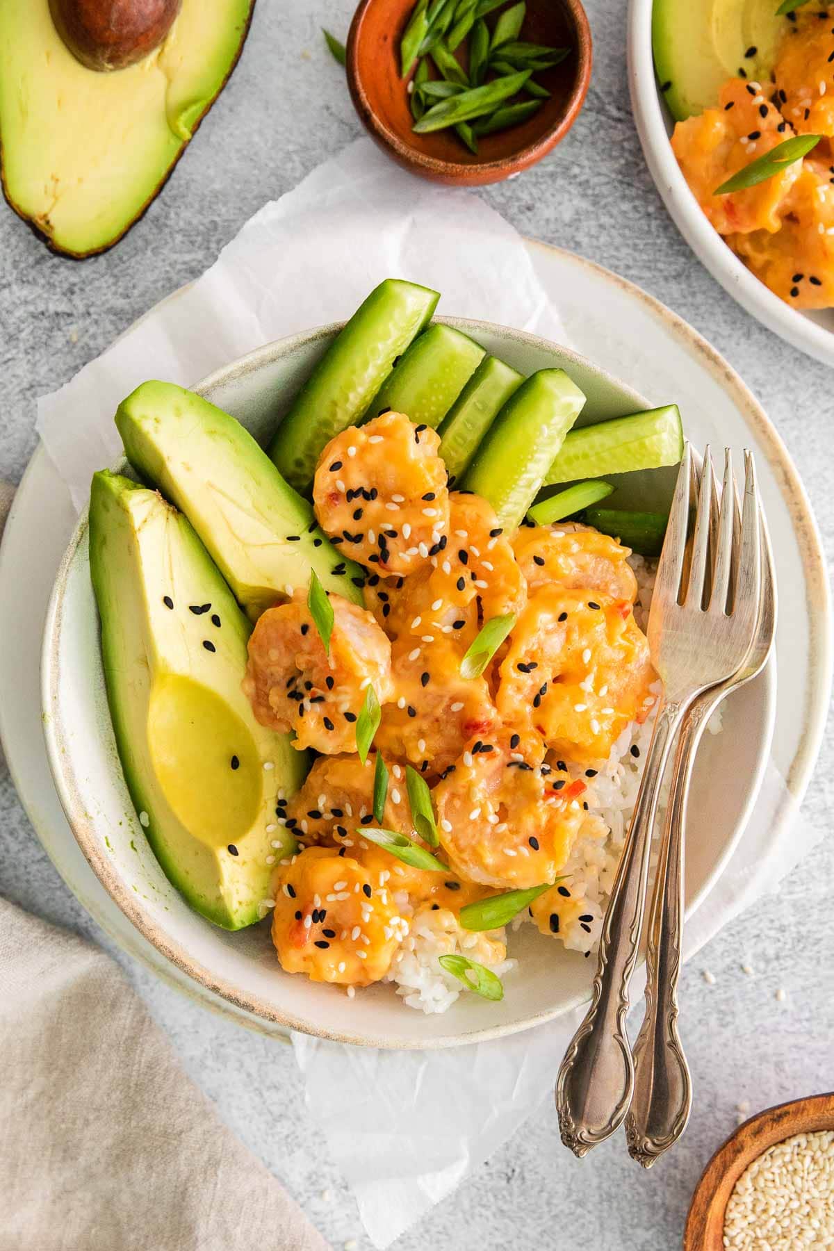white bowl with shrimp and white rice and sliced avocado and cucumber