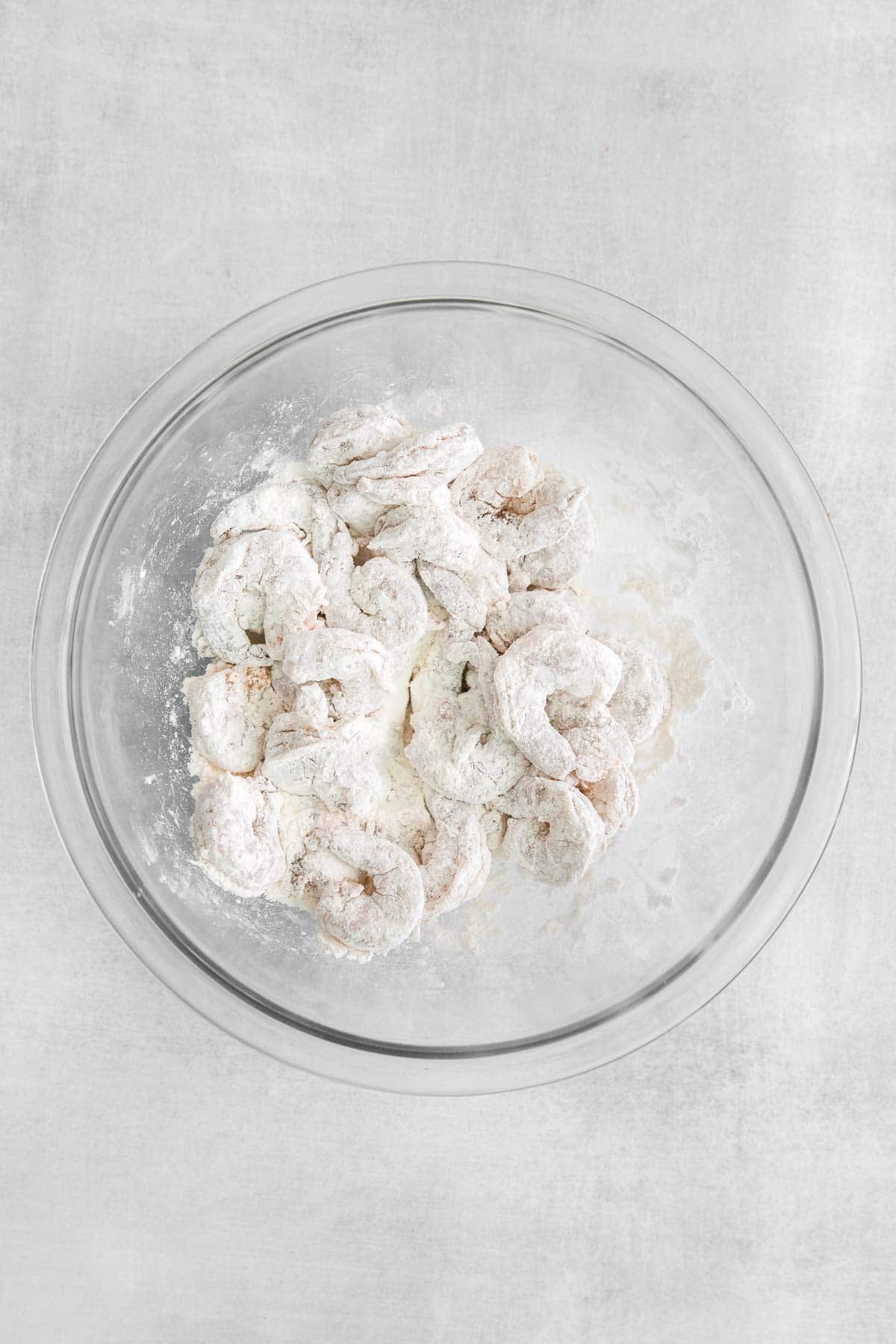 glass bowl with raw shrimp tossed in flour