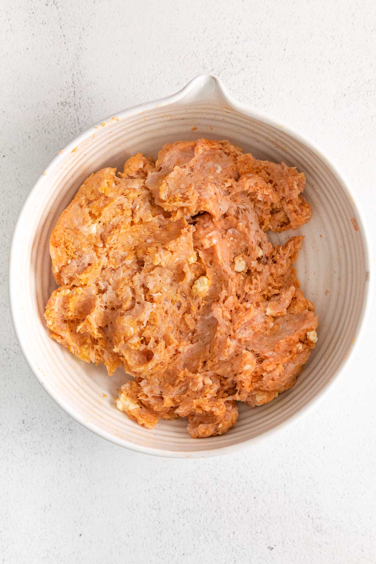 raw buffalo chicken meatball mixture in a white mixing bowl.