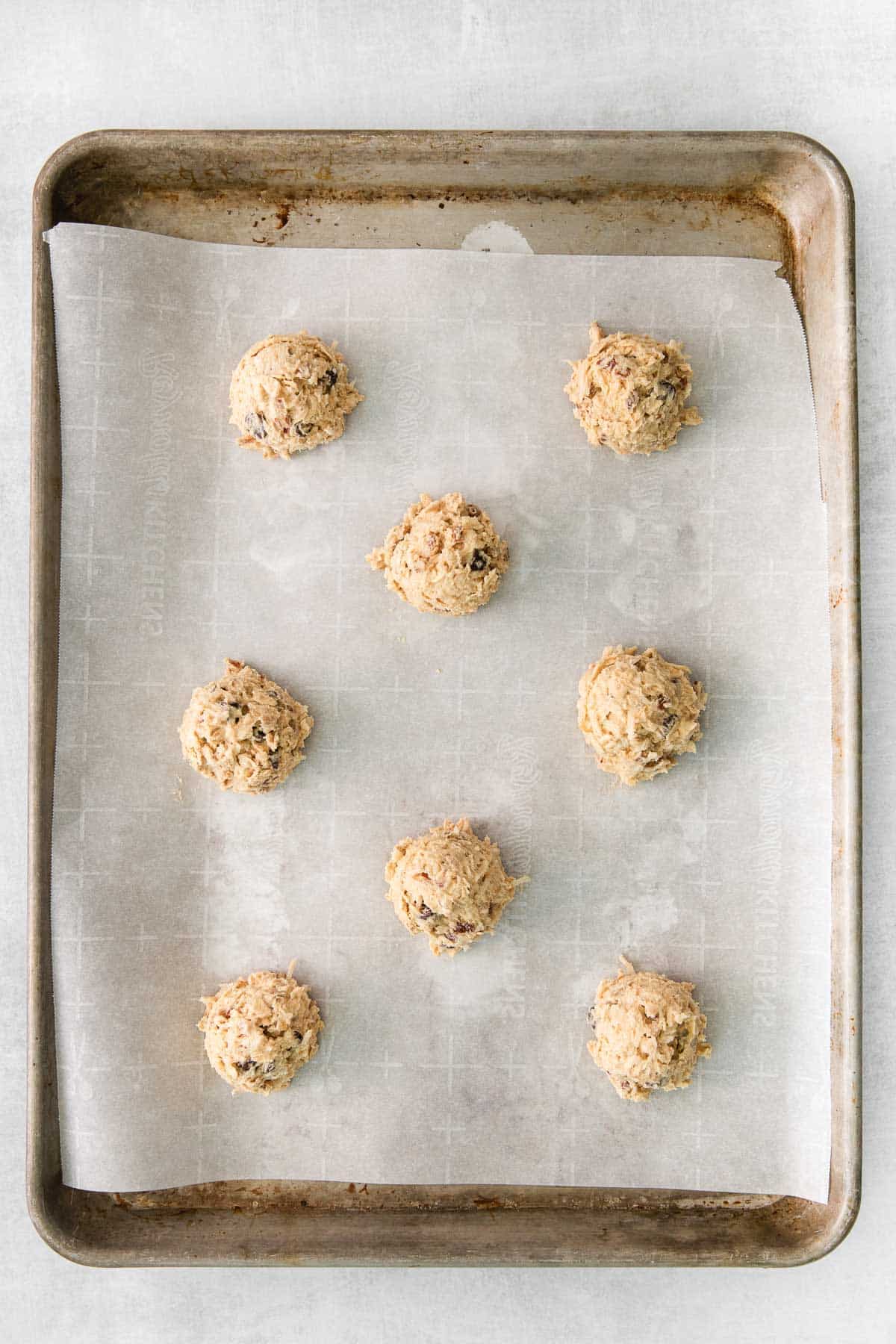 eight balls of cookie dough on parchment paper lined baking sheet