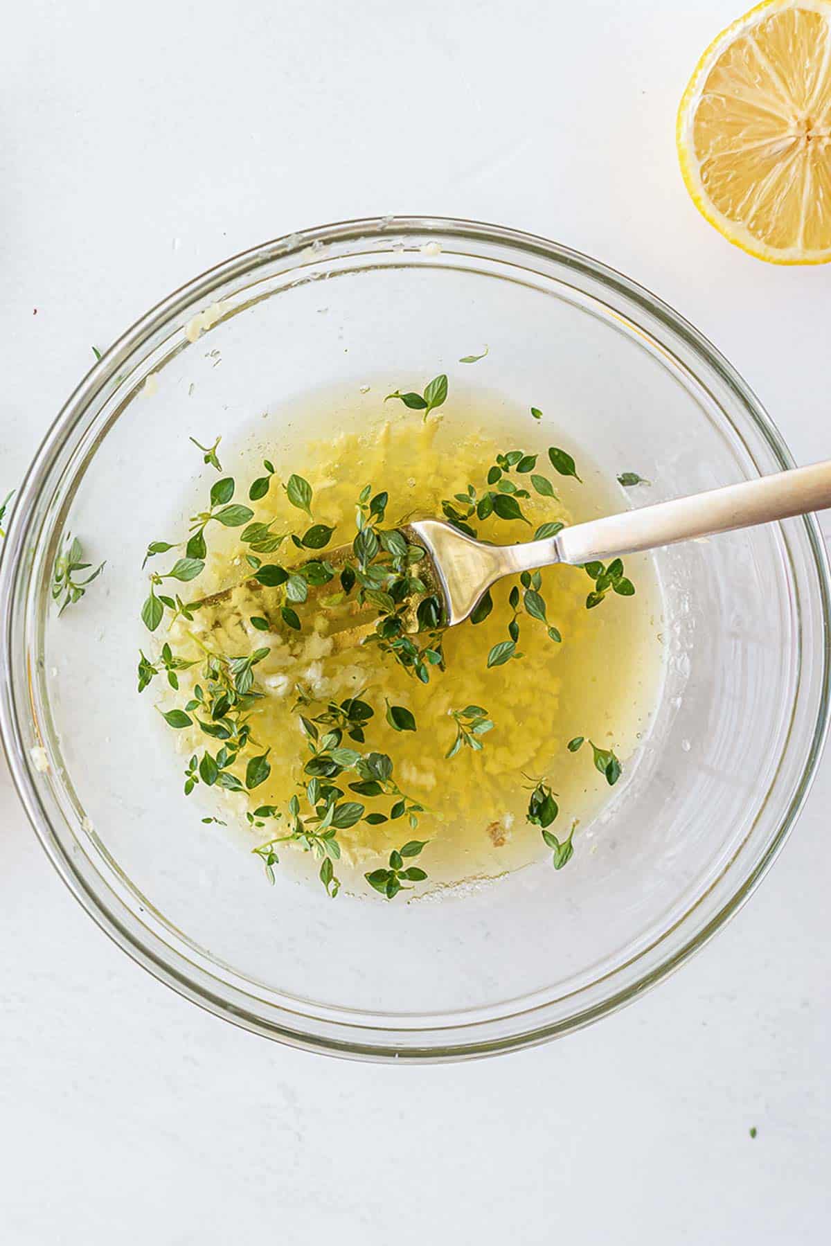 glass bowl with olive oil, minced garlic and fresh thyme