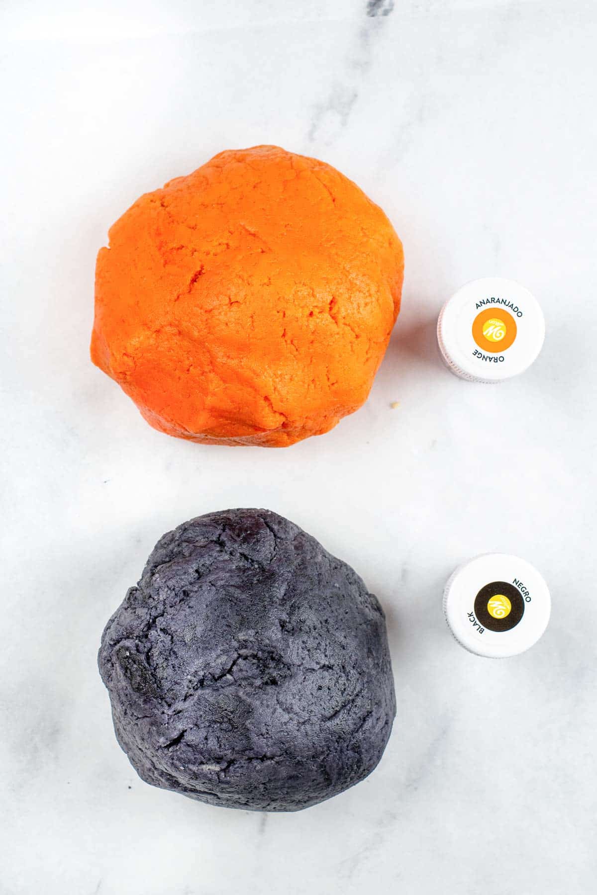 an orange ball of cookie dough and a black ball of cookie dough