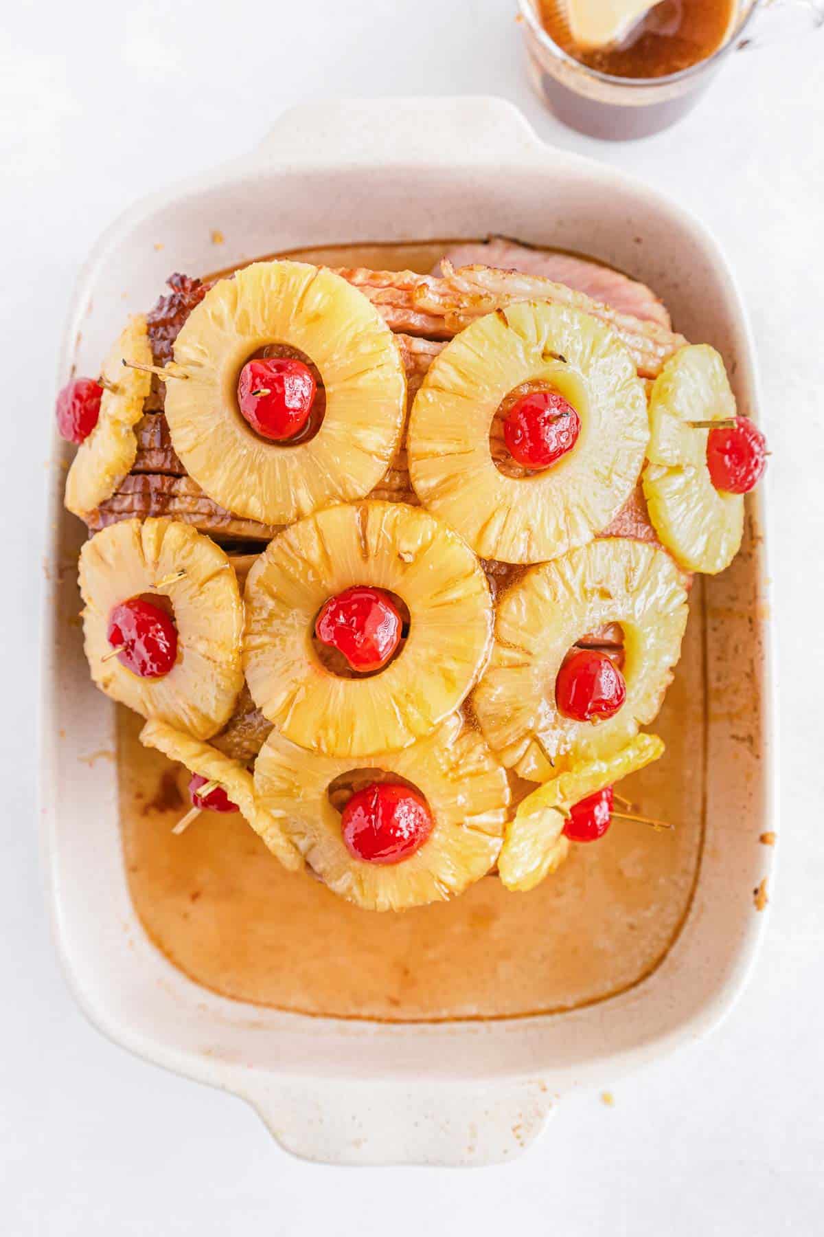 uncooked honey glazed ham topped with pineapple and cherries.