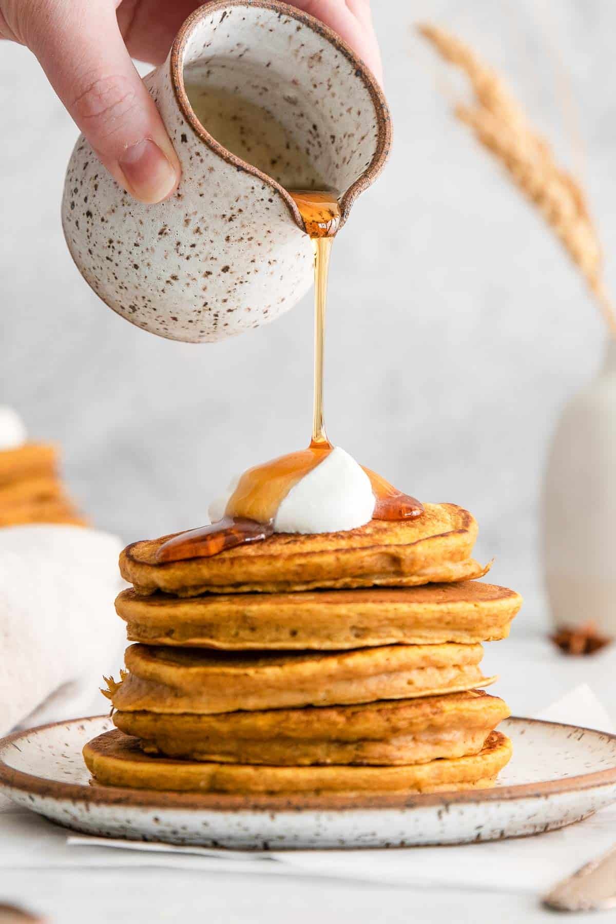 stack of five pumpkin pancakes with syrup being poured over top