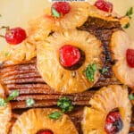 closeup of sliced baked ham with pineapple slice with cherries in the centers