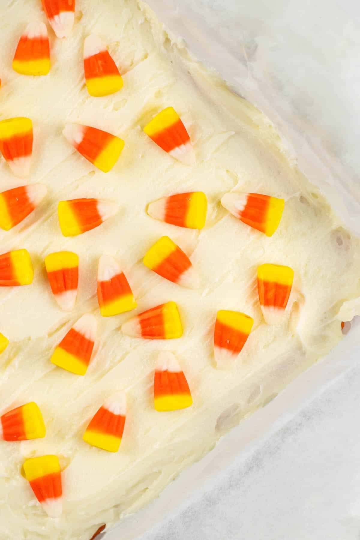 candy corn on top of cream cheese frosting in a square dish.