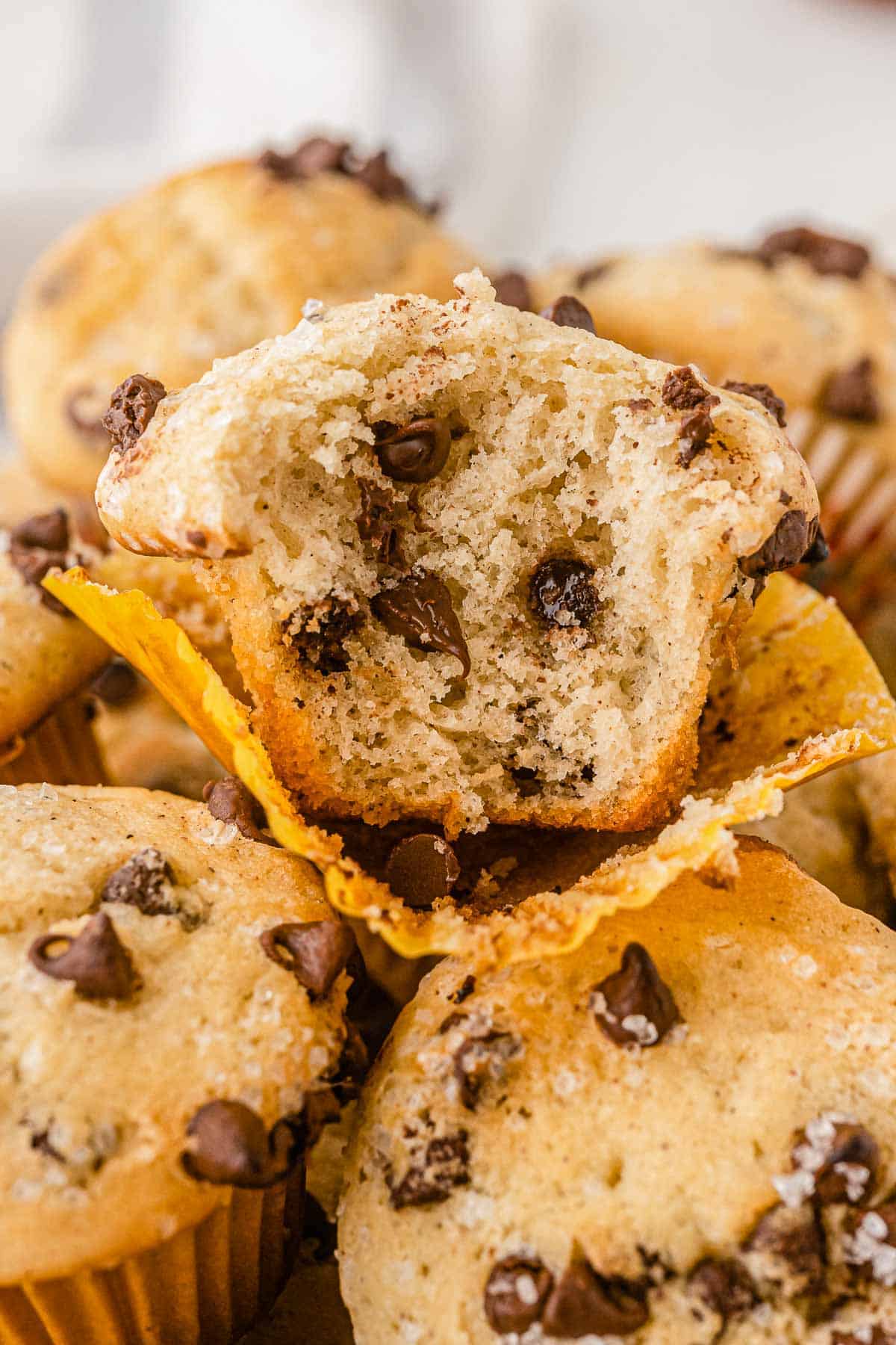 closeup of a stack of chocolate chip mini muffins with one with a bite taken out.