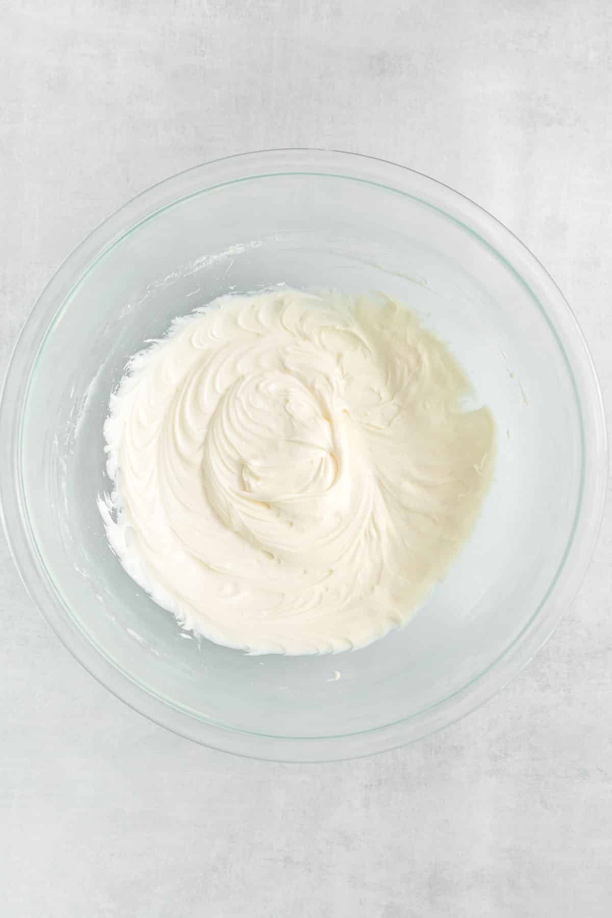 big glass mixing bowl with cream cheese blended.