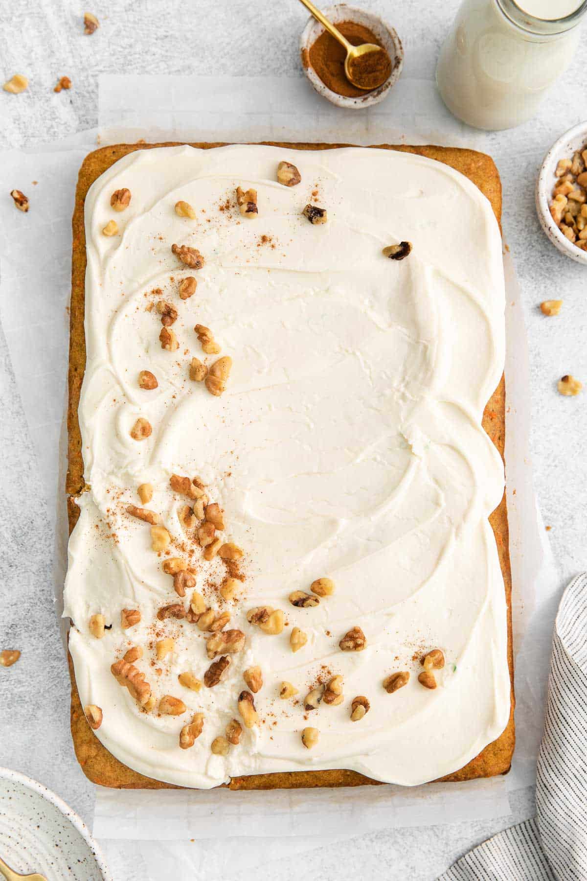 simple sheet pan carrot cake topped with cream cheese frosting and chopped pecans.