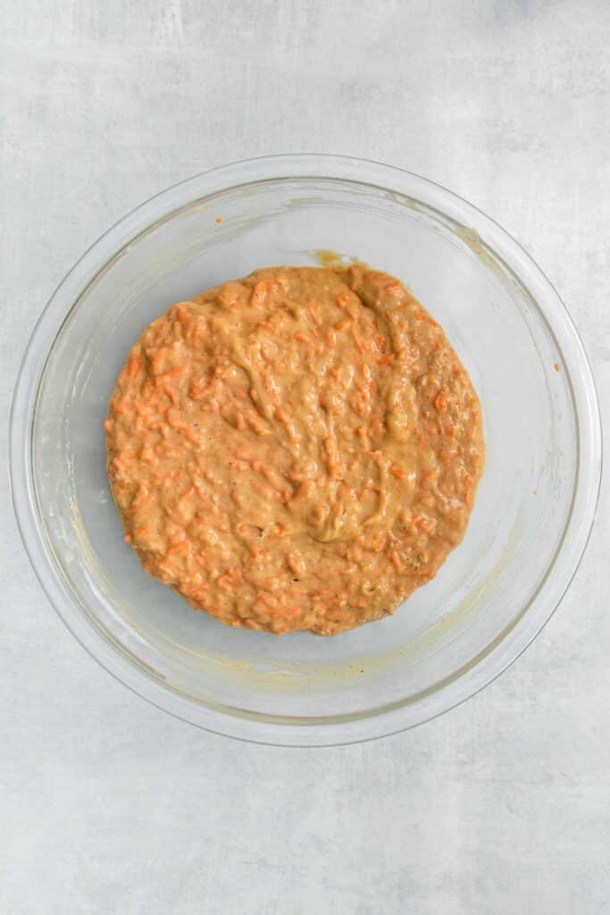 big glass mixing bowl with carrot cake batter.