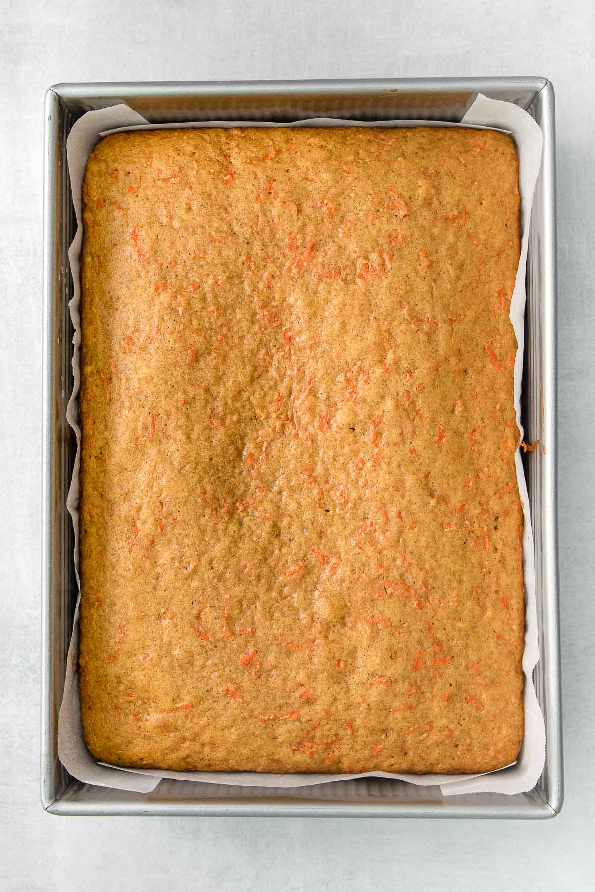 9x13 metal baking dish with sheet pan carrot cake baked.