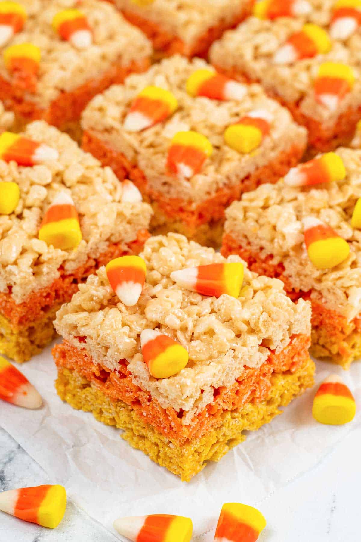 halloween candy corn rice colored rice krispie treats on white parchment paper.