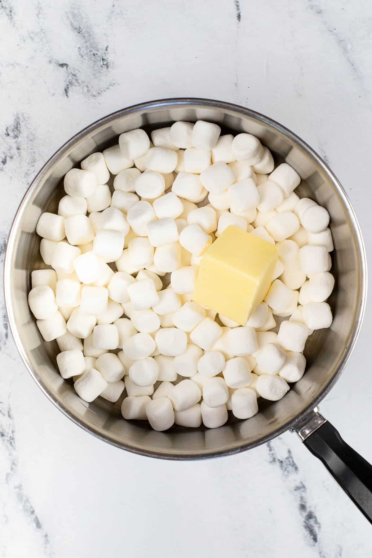 silver pot with mini marshmallows with a square of butter on top.