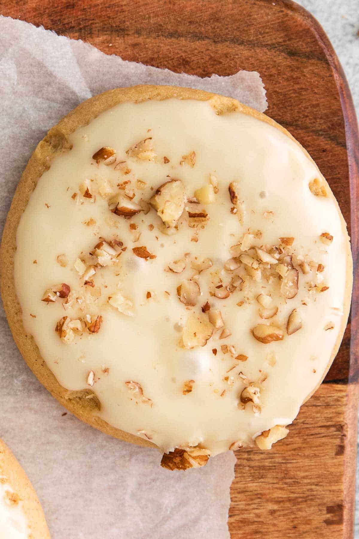 closeup of a glazed maple cookie topped with chopped pecans.
