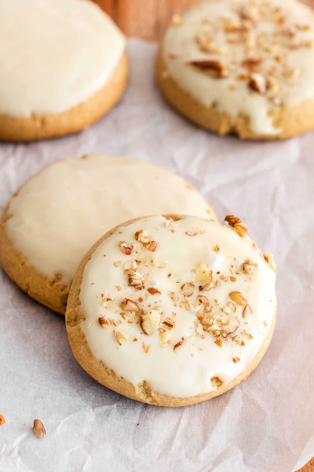 closeup of two cookies with maple frosting and chopped pecans crumbs.
