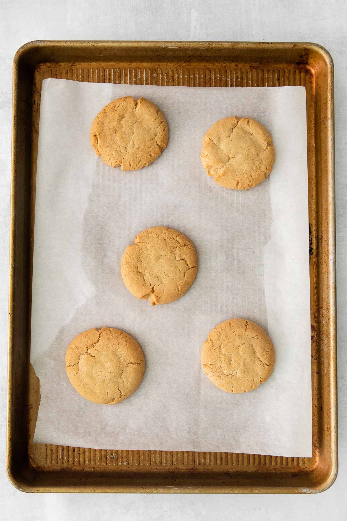 five maple cookies on a parchment lined baking sheet