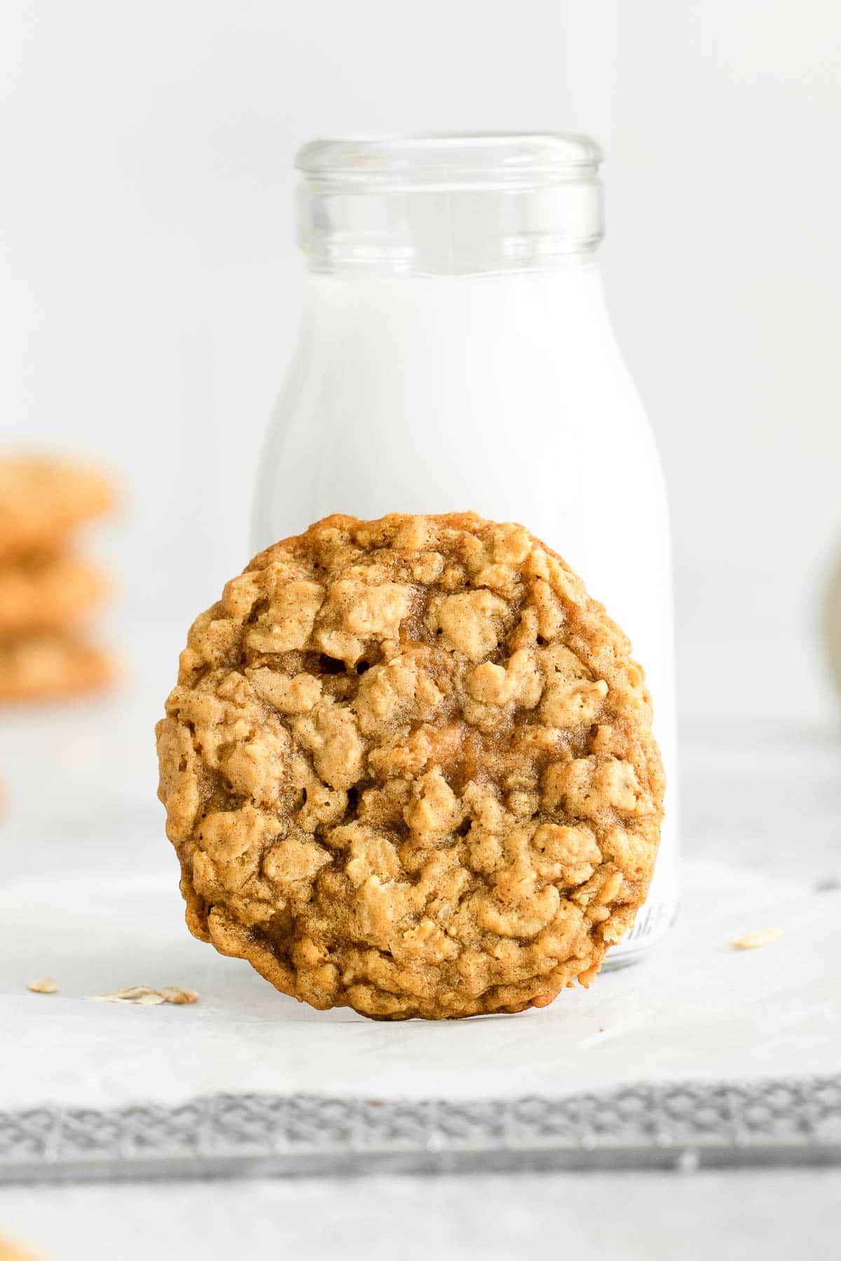one pumpkin oatmeal cookie leaning up against a jar of milk.