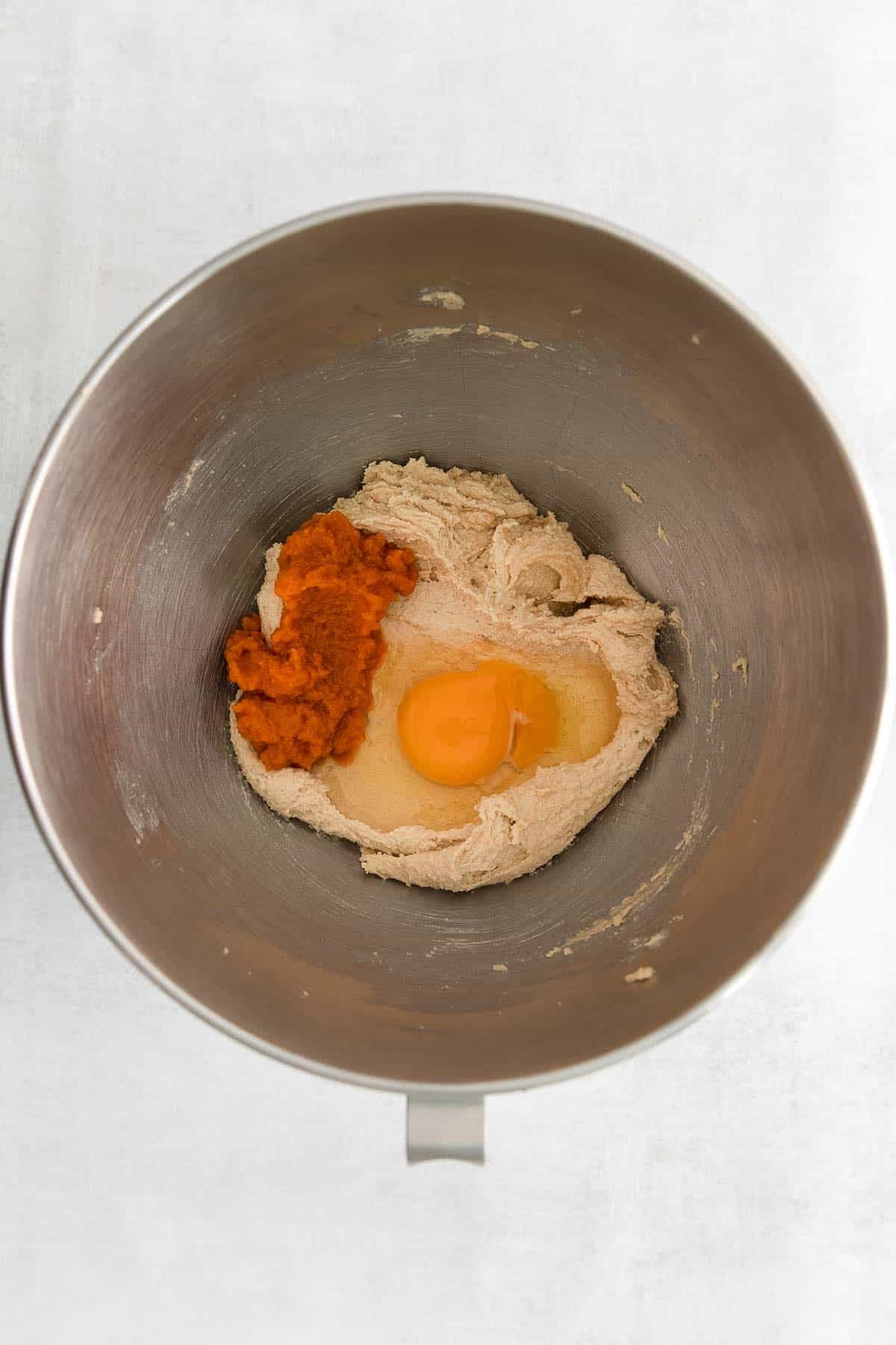 silver mixing bowl with butter and sugar creamed together with pumpkin puree and a raw egg.