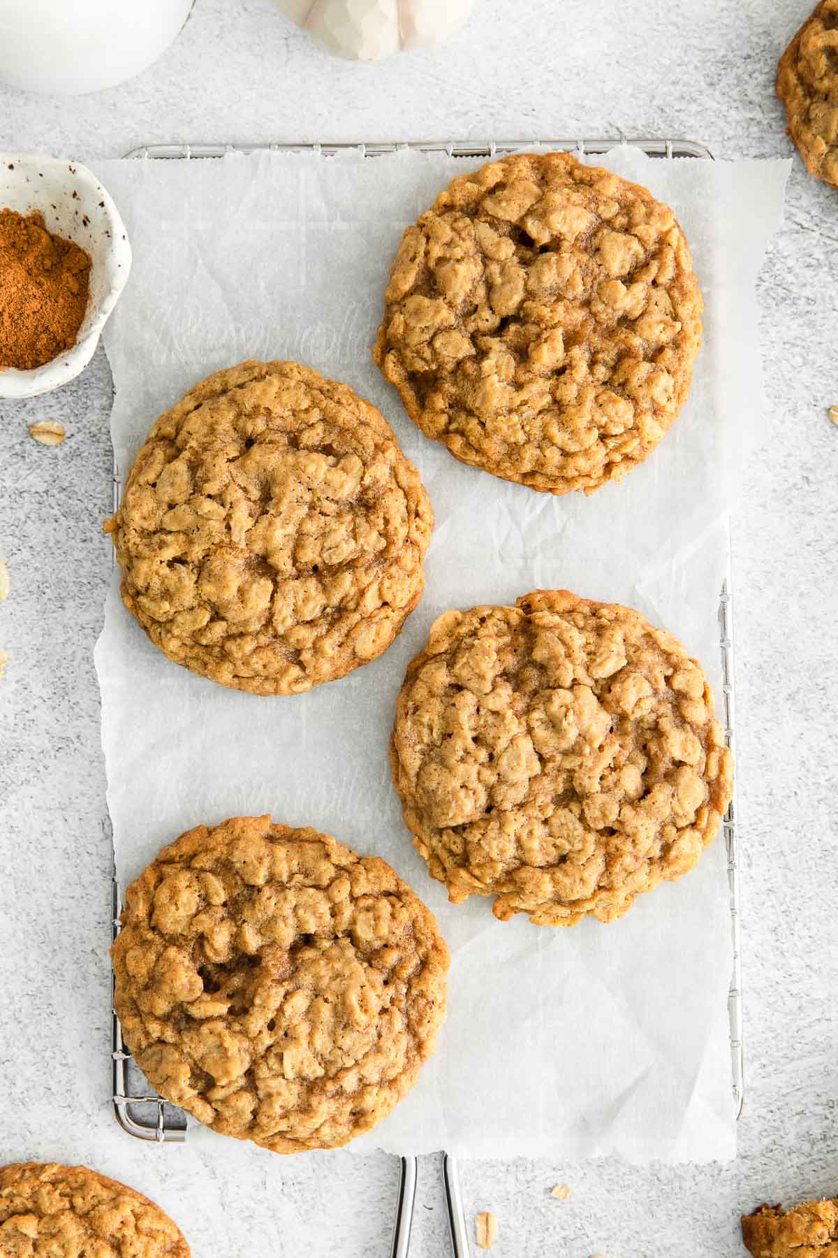 closeup of four pumpkin oatmeal cookies on white parchment paper.